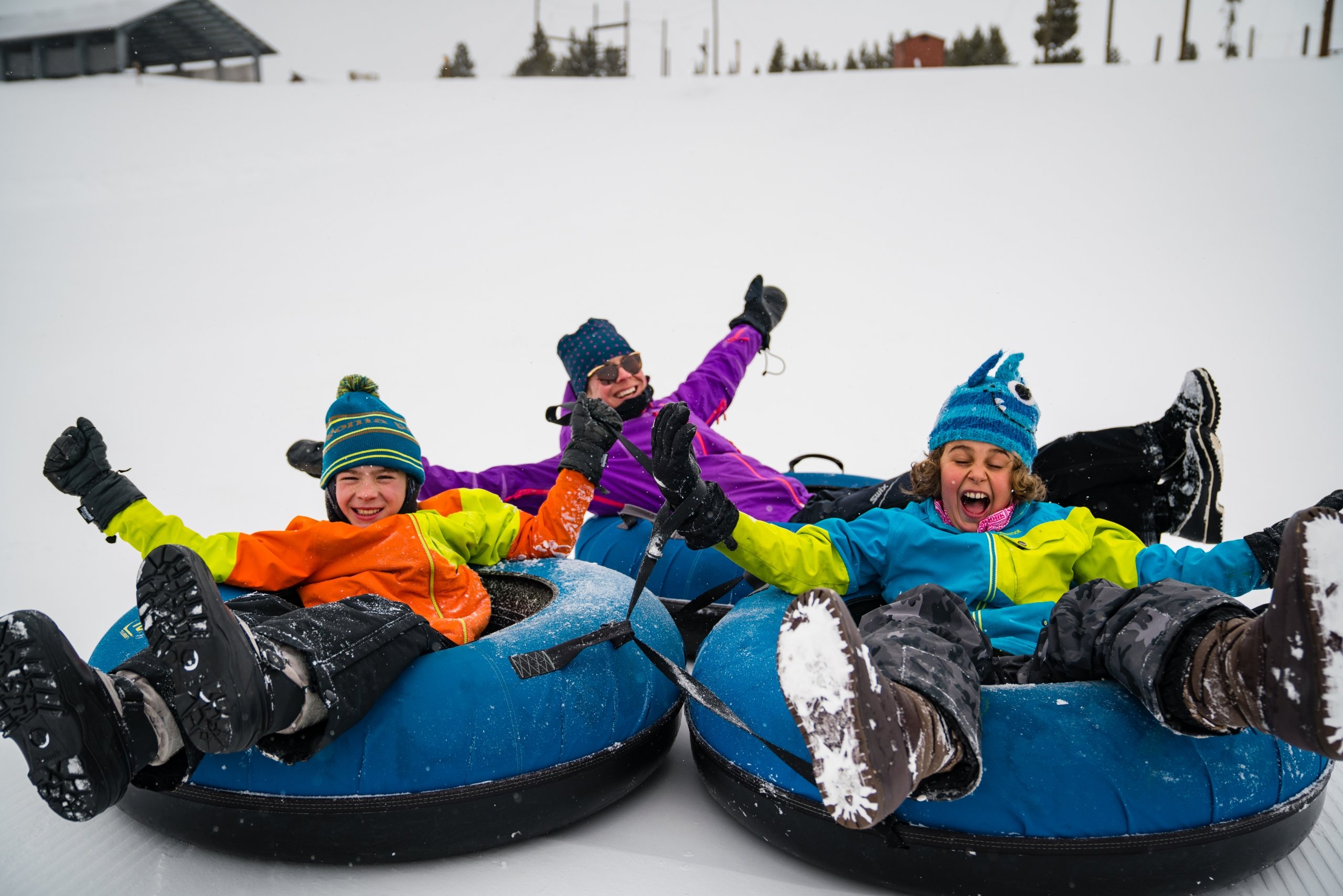 A family of three enjoying time together on a winter tubing hill